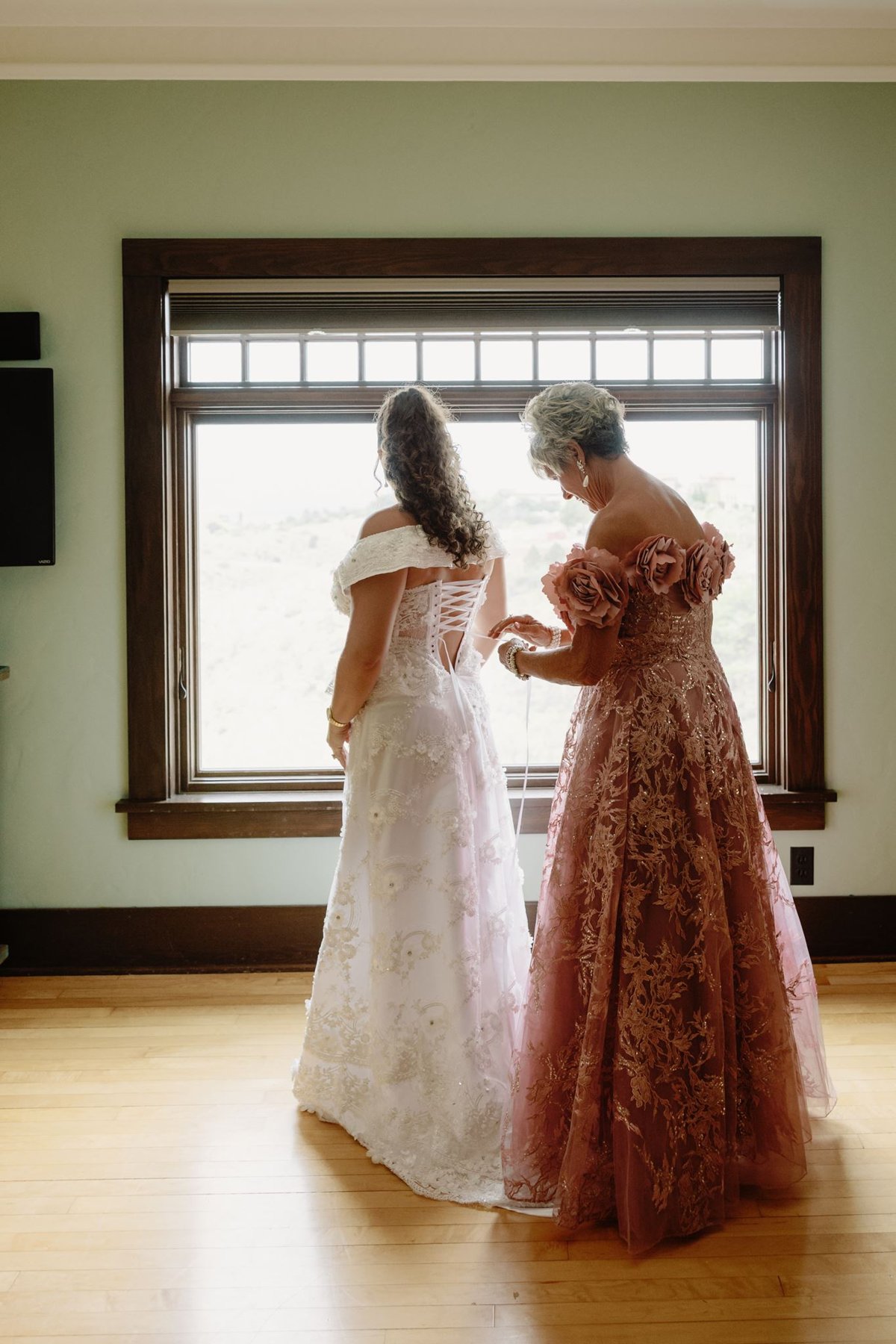 Abigail’s mother lacing the back of her wedding dress by a window