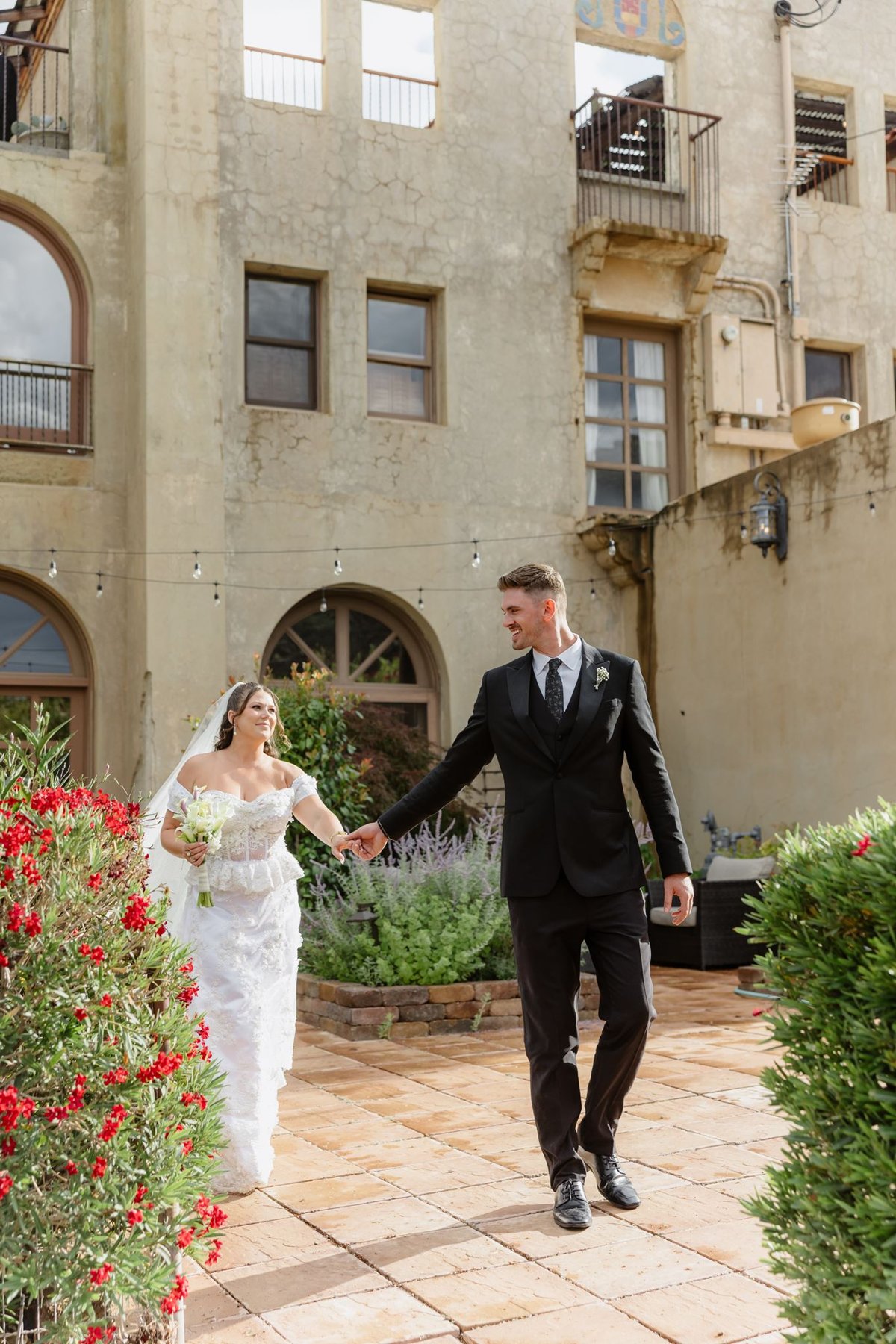 Abigail and Ethan walking through the garden beside red flowers