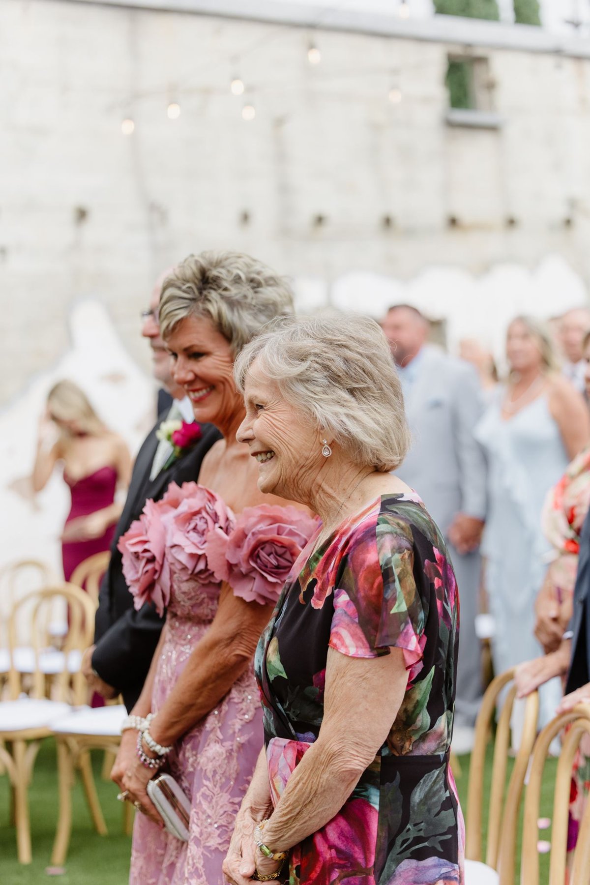 Abigail’s mother and a guest smiling during the wedding ceremony