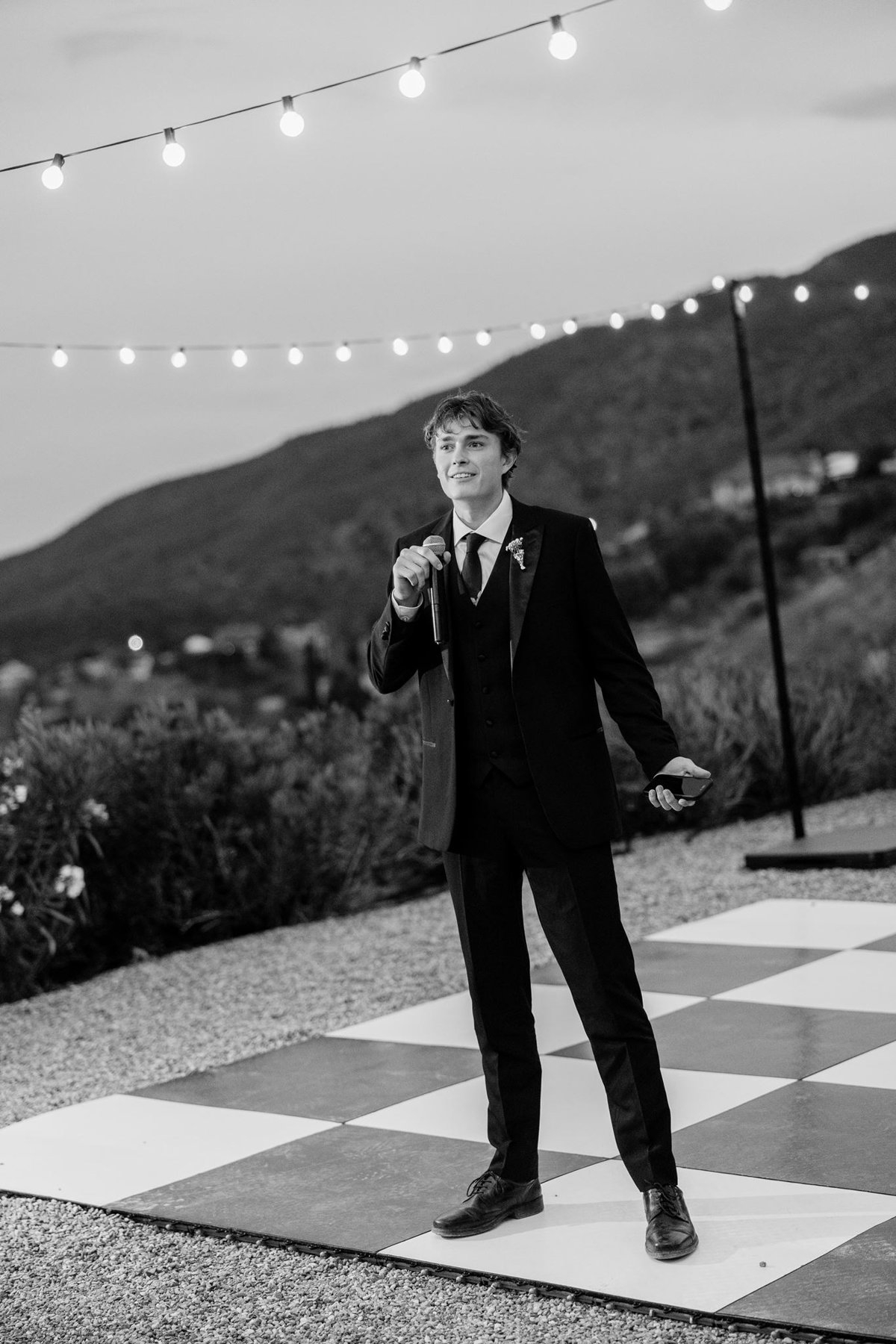Black and white photograph of a wedding party member giving a toast