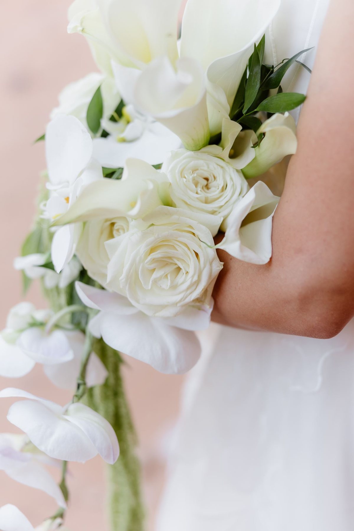 Close view of Maggie’s cascading white bridal bouquet and greenery against her wedding dress