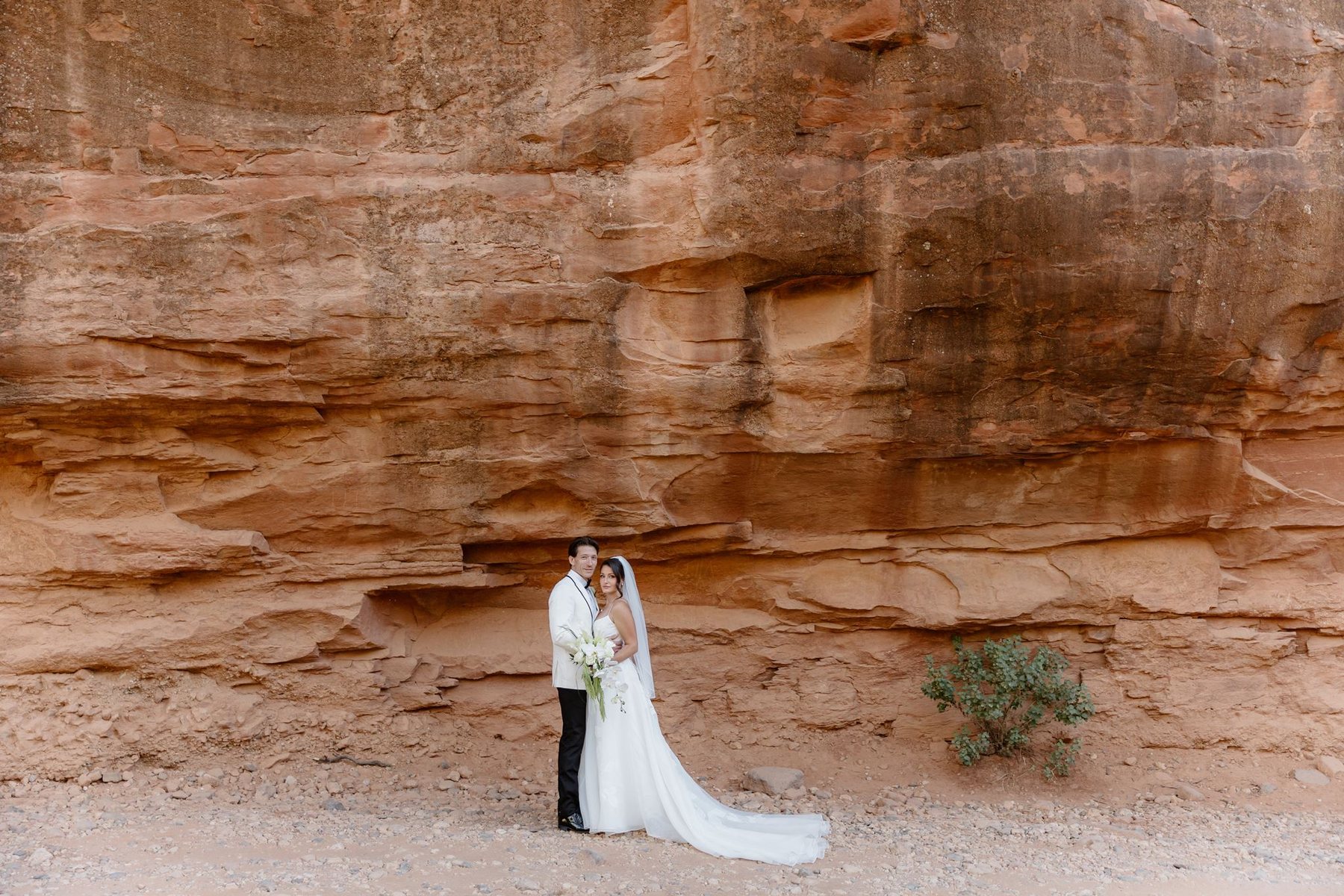 Wide portrait of Maggie and Brandon together beneath a layered red sandstone wall