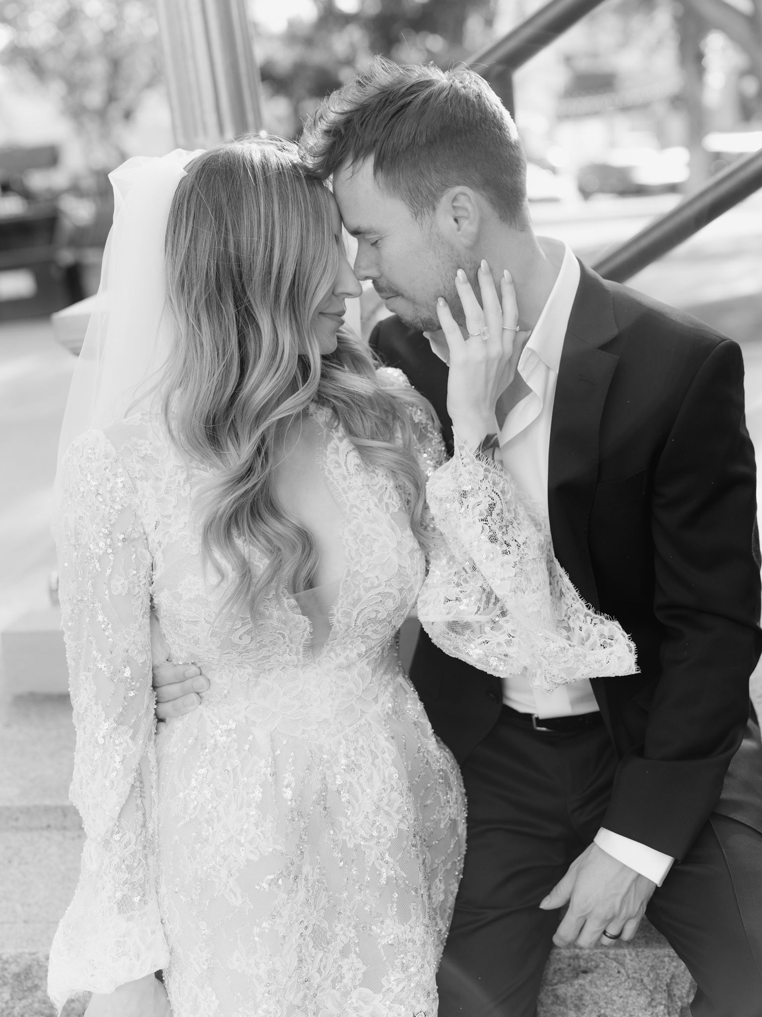 Black and white portrait of Erica and Evan kissing beside the staircase railing.