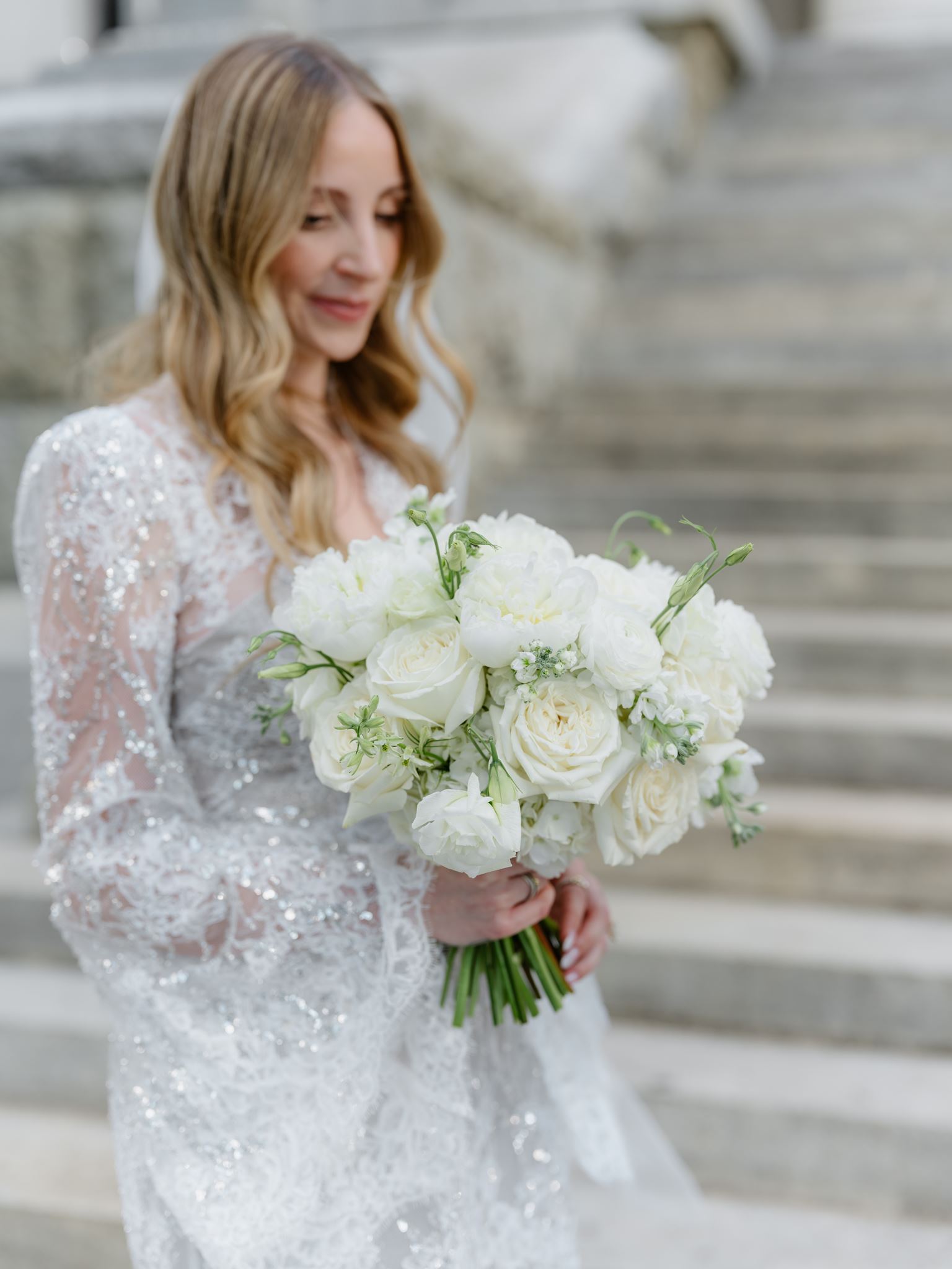 Erica holding her white bouquet in front of the courthouse steps.