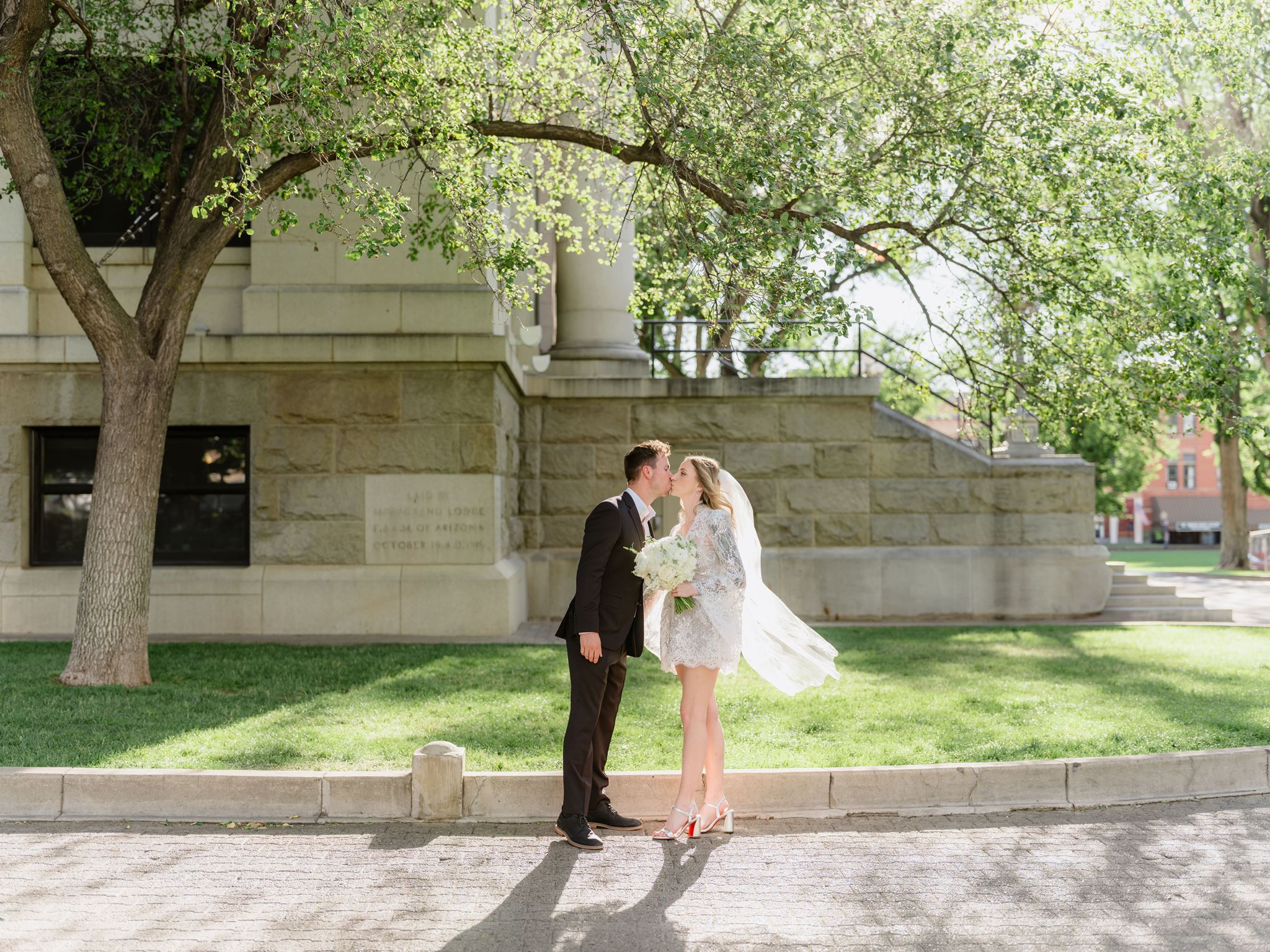 Erica and Evan kissing beneath a tree beside the Prescott courthouse.