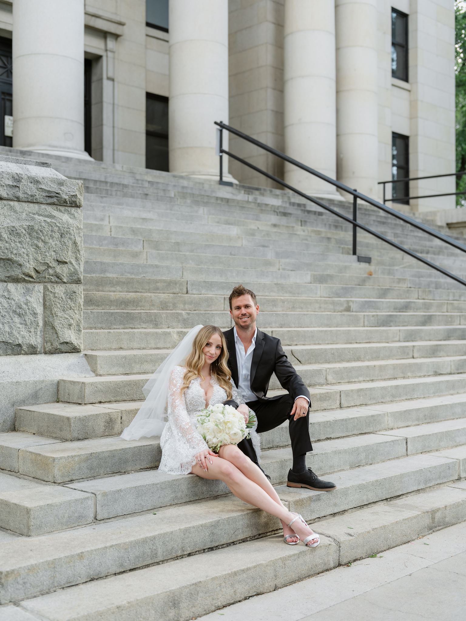 Erica and Evan sitting together on the broad stone courthouse steps.