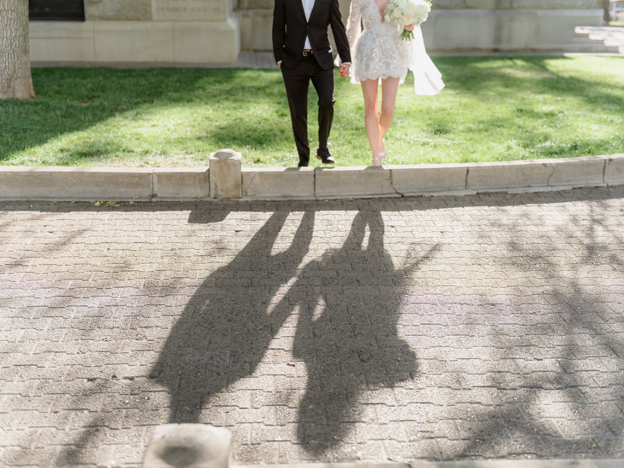 Long shadows of the couple holding hands beside Courthouse Plaza.