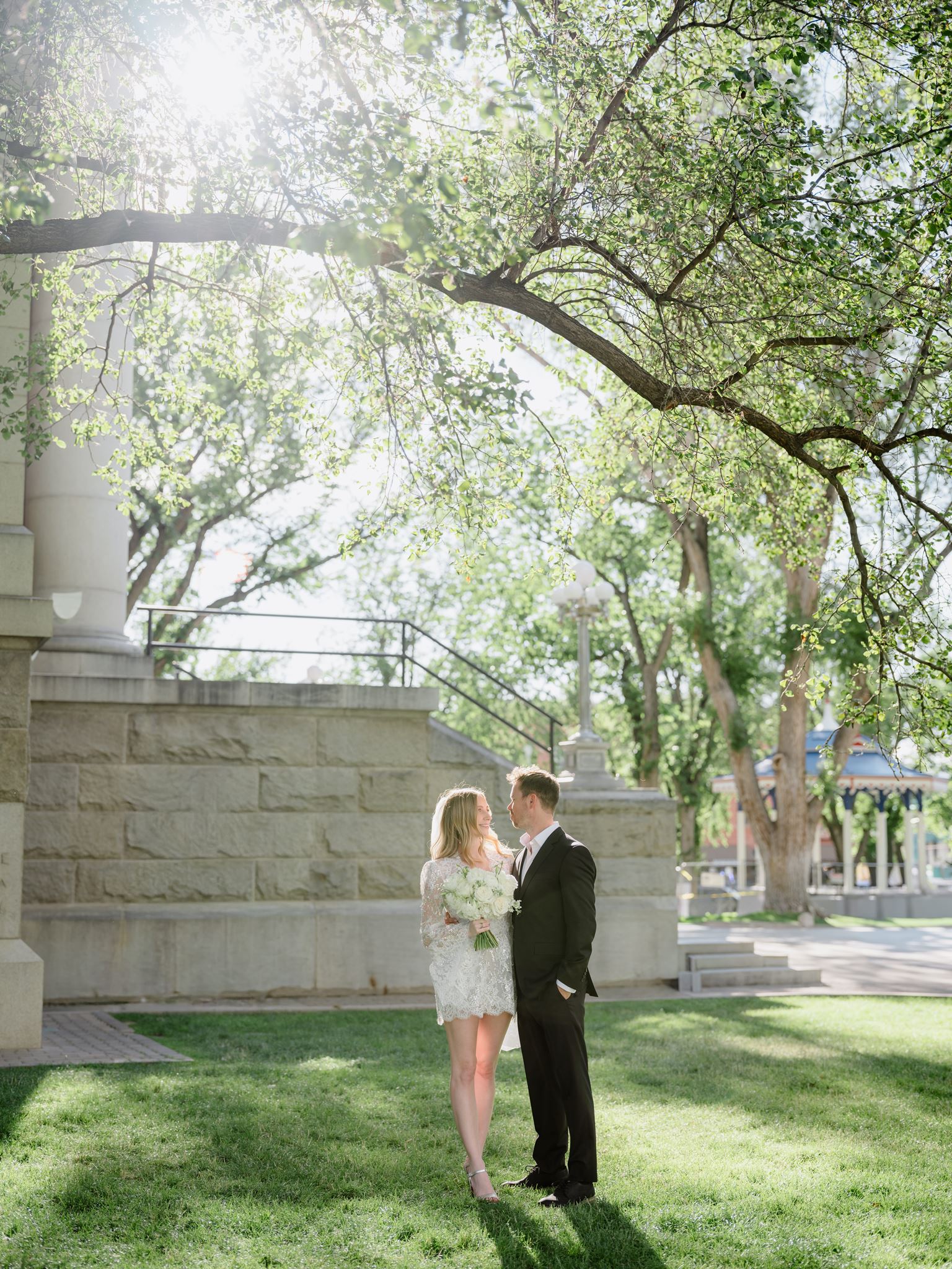 Erica and Evan facing each other under trees beside the courthouse.