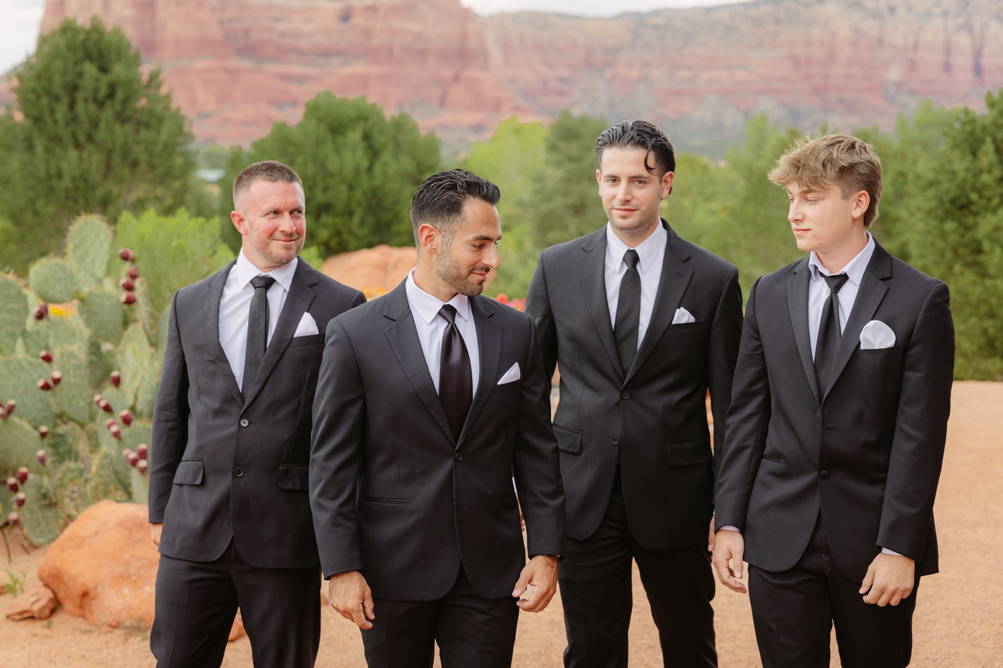 Alexander laughing with his groomsmen in black suits before the wedding ceremony