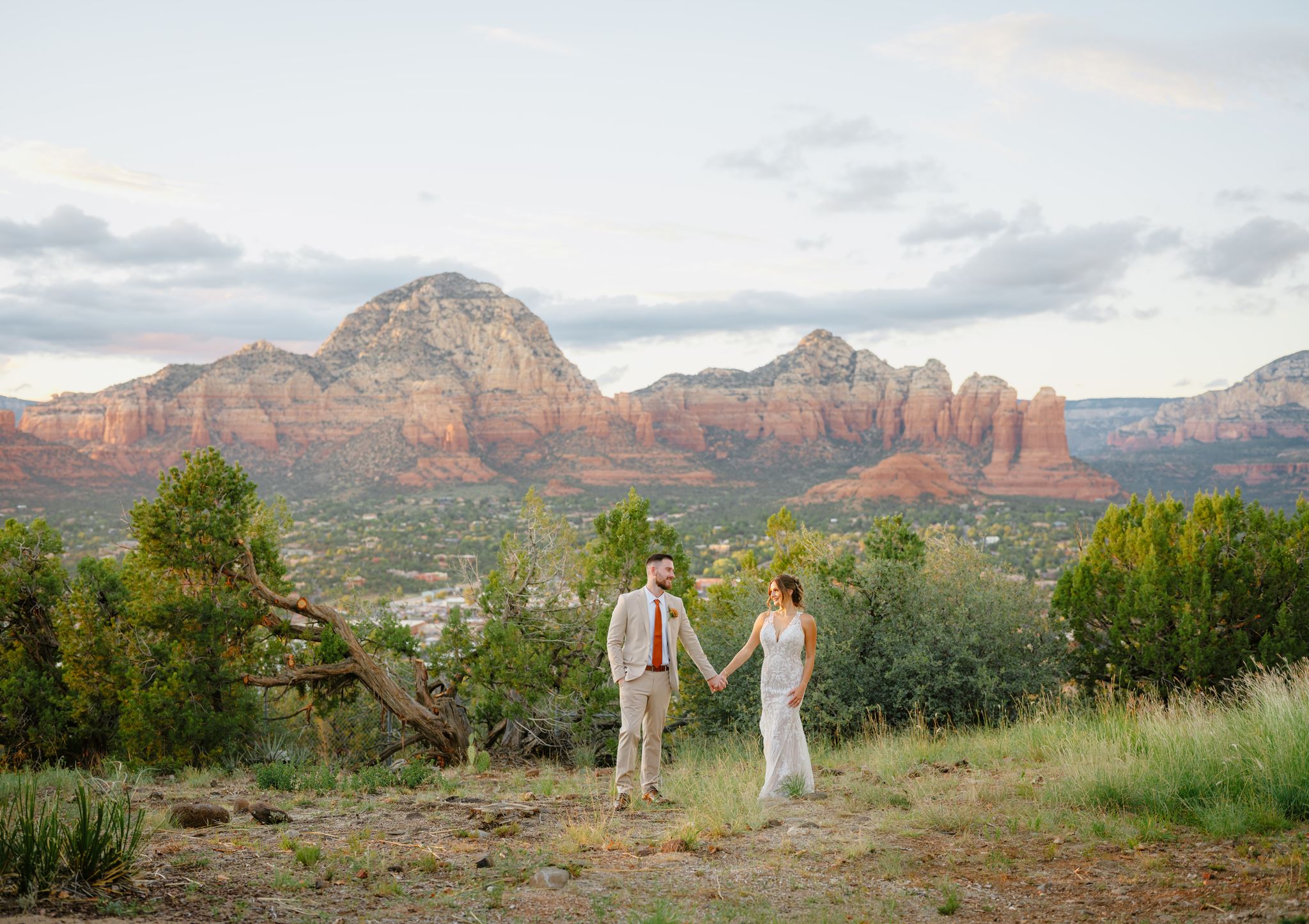 Kylie and Peyton holding hands with Sedona red rocks behind them.