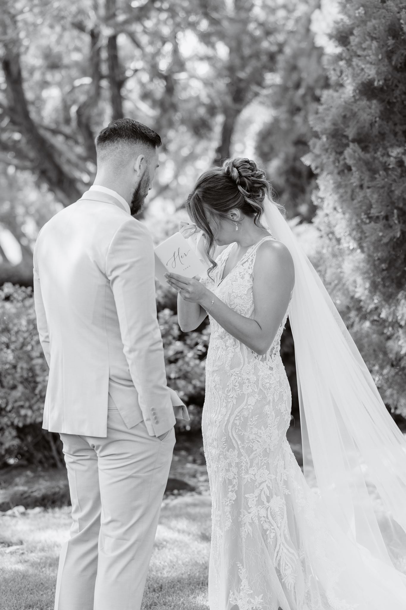 Black-and-white photograph of Kylie wiping away a tear during private vows.