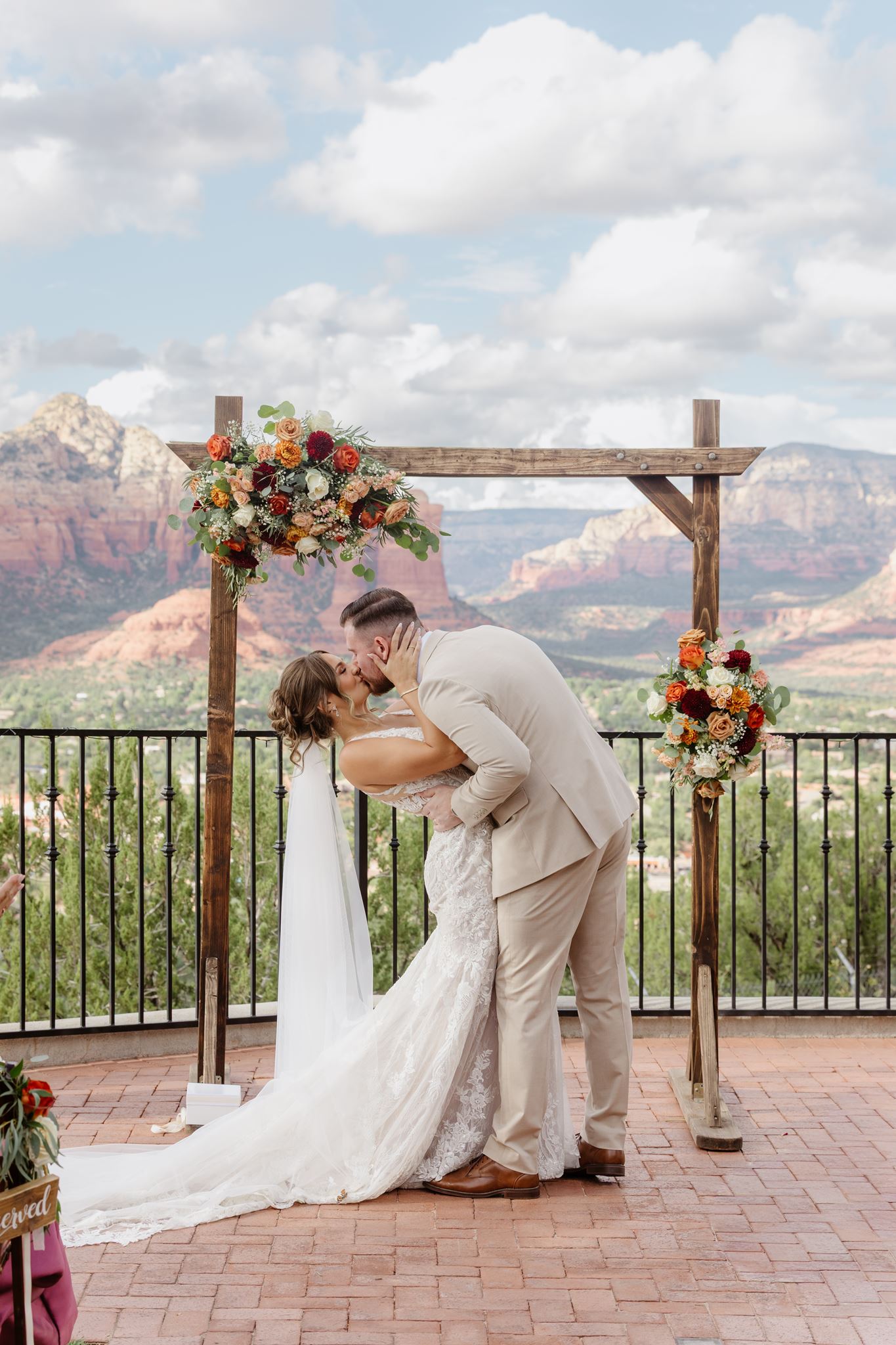 Kylie and Peyton sharing their first kiss beneath a floral wedding arbor.